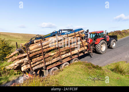 Un tracteur tractant une remorque avec une charge lourde de billes jusqu'à une colline sur Exmoor au-dessus de la vallée de l'eau au nord de Chetsford Exford, Somerset UK Banque D'Images