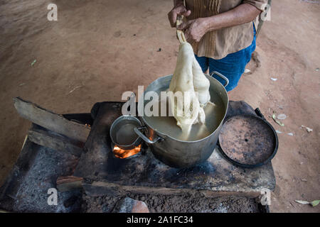 Femme d'un des cuisiniers quilombo un poulet sur une cuisinière rustique en plein air Banque D'Images