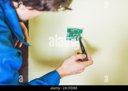 Electricien installation d'un thermostat électrique dans une maison neuve. Banque D'Images