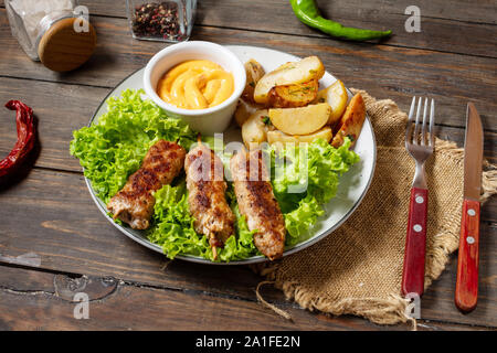 Shish kebab grillé servi avec pommes de terre rissolées et la sauce sur un fond de bois Banque D'Images