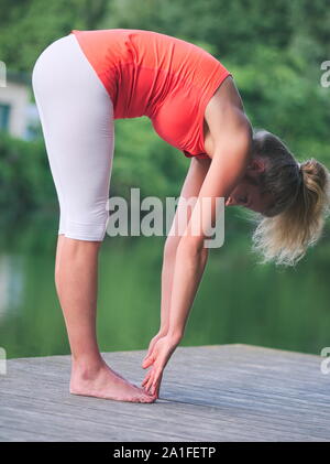 Femme d'une trentaine d'Faire du yoga dans le parc on a Pier Banque D'Images