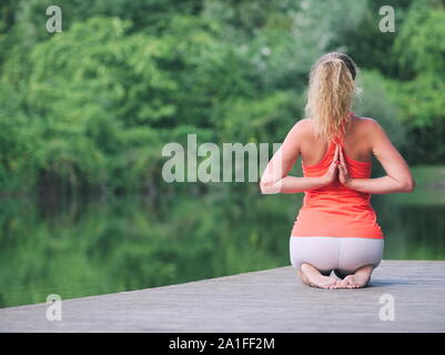 Femme d'une trentaine d'Faire du yoga dans le parc on a Pier Banque D'Images