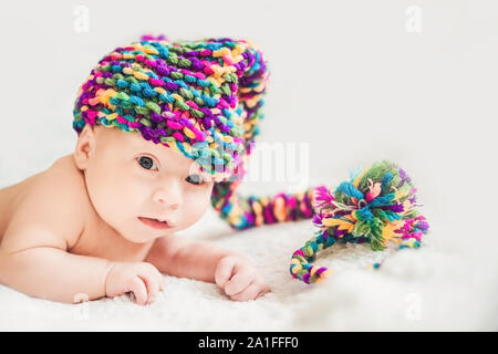 Bébé nouveau-né dans le Nouvel An Cap gnome repose sur un manteau blanc. Banque D'Images