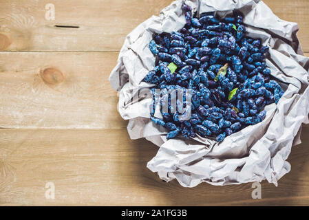 Chèvrefeuille frais fruits berry bleu avec la feuille sur un fond de bois. Banque D'Images