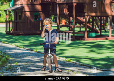 Garçon jouant avec fidget spinner. Spinner spinning enfant dans l'aire de jeux. Arrière-plan flou. Banque D'Images