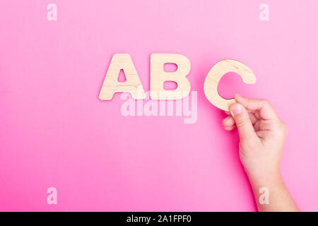 ABC des lettres dans les mains de l'enfant sur fond rose. Banque D'Images