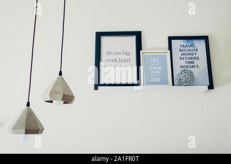 Des cadres avec des citations de motivation et d'inspiration mis sur étagères par des chandeliers. Design d'intérieur. Décor à la maison Banque D'Images