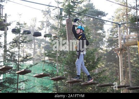 Adolescent bénéficiant d'escalade à un parc aventure accrobranche Banque D'Images