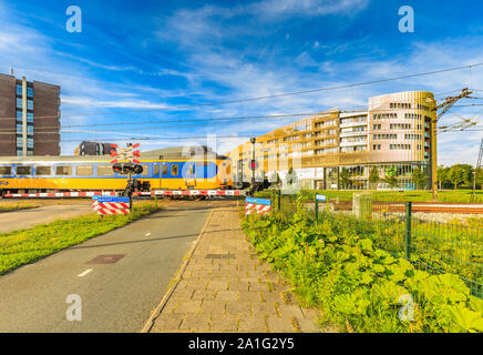 Laan der Continenten, Alphen aan den Rijn, Zuid Holland, les Pays-Bas, le 23 août 2019 : passage à niveau des chemins de fer néerlandais et de train qui passe, fermé Banque D'Images