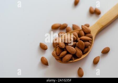 Les écrous d'amandes séchées en cuillère en bois sur fond blanc.amandes Pelées. Banque D'Images