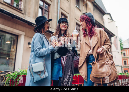 Trois amies ayant des boissons à l'extérieur. Les femmes clinking café, jus d'orange et tasses à thé Banque D'Images