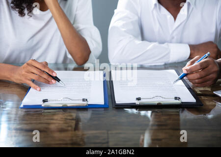 Deux entrepreneurs travaillant sur papier du contrat In Office Banque D'Images