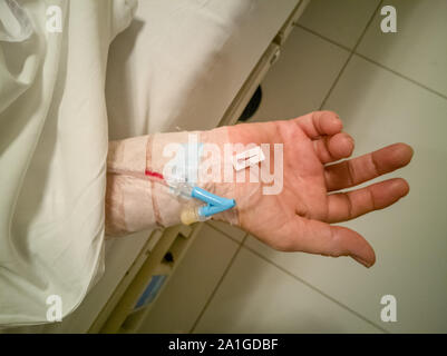 Soft focus main de la femme de race blanche avec une ligne intraveineuse (IV) sur le lit dans une clinique (hôpital) Banque D'Images