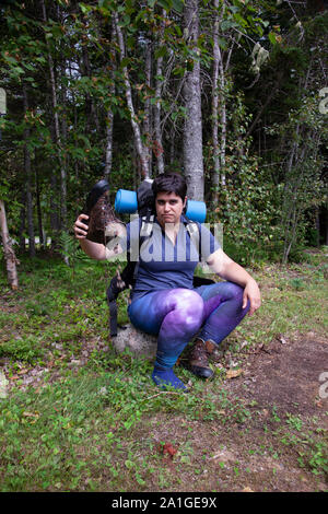 Femme assise sur un rocher la coulée de saleté et de sable hors de son démarrage images randonnée Banque D'Images