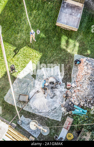 Vue de dessus d'authentique builder hommes travaillant avec pelle au cours de béton mortier solution préparation dans mixer at construction site Banque D'Images
