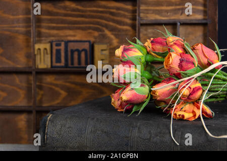 Bouquet de roses orange sur le vieux livre avec word temps dans la typographie en bois type Banque D'Images