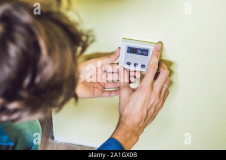 Electricien installation d'un thermostat électrique dans une maison neuve. Banque D'Images