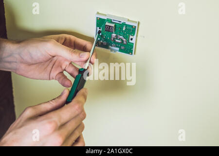 Electricien installation d'un thermostat électrique dans une maison neuve. Banque D'Images