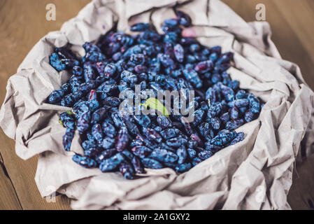 Chèvrefeuille frais fruits berry bleu avec la feuille sur un fond de bois. Banque D'Images