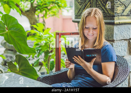 Belle femme de commander à partir d'un menu dans un restaurant et de décider quoi manger. Banque D'Images