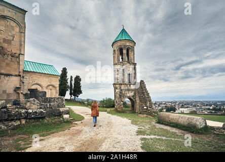 Femme marche à la chapelle de la tour de l'église Bagrati à ciel couvert à Kutaisi, Géorgie Banque D'Images