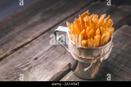 Frites dans une tasse de métal sur un fond rustique. Portion de frites. Fast Food snack délicieux Banque D'Images