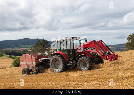 Un agriculteur de la mise en balles de paille sur un Après-midi nuageux dans Aberdeenshire Banque D'Images