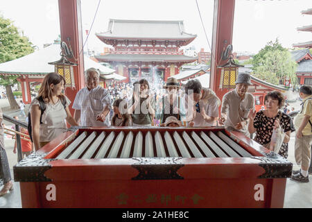 Les touristes prier autour de : saline box' un money offre fort à l'extérieur hall principal du Temple de Senso-ji, Asakusa, Tokyo, Japon. Banque D'Images