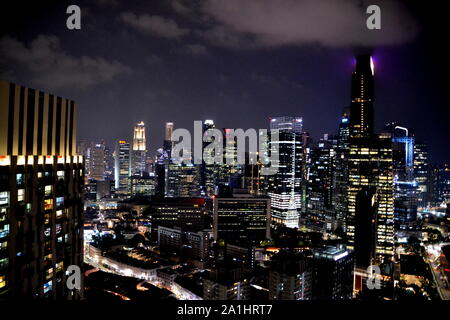 Skyline de Singapour de nuit avec des gratte-ciel illuminés et nuageux ciel sombre Banque D'Images