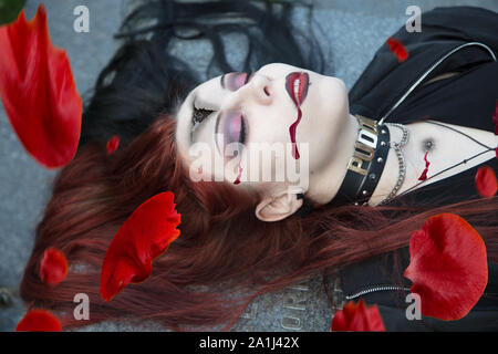 Mystérieuse jeune femme sombre habillés en costume goth noir situé sur l'ancien cimetière de l'église médiévale à tombstone Banque D'Images