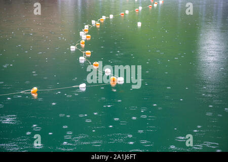 Corde avec restriction blanc et jaune marqueurs sur surface de l'eau pour l'interdiction de baignade en lac profond ou de la mer. Banque D'Images