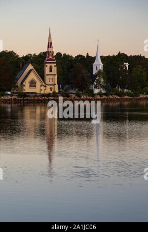 Trois églises le long des quais de la baie Mahone, reflétée dans l'eau au lever du soleil sur un beau jour. Banque D'Images