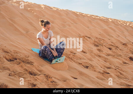 Jeune femme roule sur une piste de luge dans le traîneau dans le désert. Banque D'Images