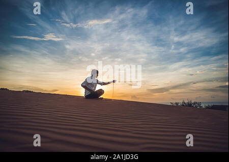 Un homme verse du sable dans le désert. Entre les doigts de sable de la notion. Banque D'Images