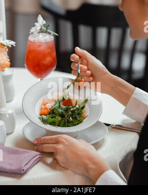 Femme mangeant une salade de légumes à la tomate, poivron, roquette et aneth Banque D'Images