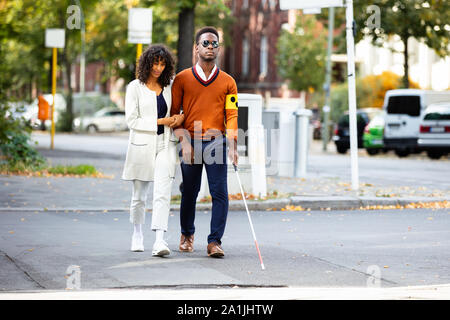 Jeune femme aider aveugle sur Street Banque D'Images