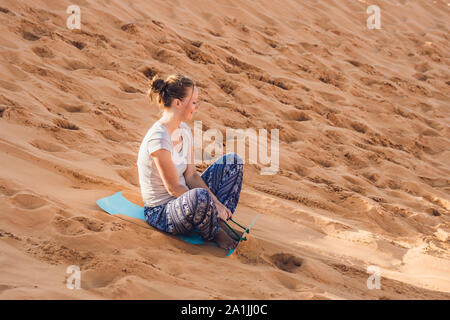 Une jeune femme roule sur un toboggan dans le traîneau dans le désert Banque D'Images