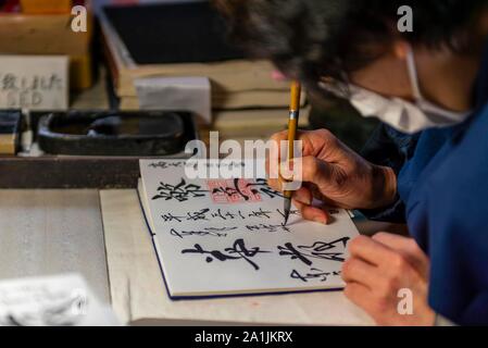 Femme écrit en caractères japonais, calligraphie, des charmes de acheter en Temple Todaiji, Japon, Nara, Japon Banque D'Images