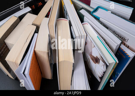 Une série de livres disposés comme un ventilateur sur une surface noire vu de dessus Banque D'Images