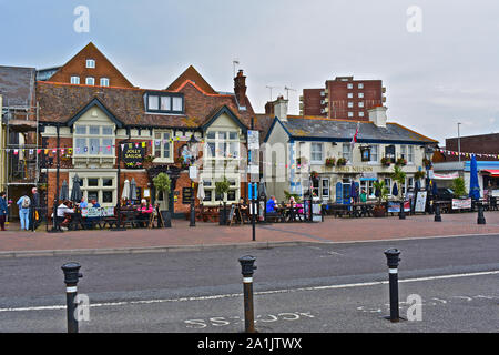 Les gens assis à l'extérieur des pubs le long du front de mer à Poole, y compris le Jolly marin et le Lord Nelson. D'autres se promener le long de la rue. Banque D'Images