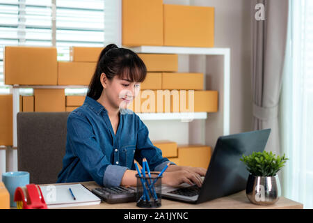 Charmante belle asiatique propriétaire adolescent femme d'affaires travailler à la maison pour faire des achats en ligne, à l'ordre dans un ordinateur portable avec l'équipement de bureau, entreprene Banque D'Images