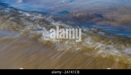 Vagues sur la grève acquise avec une vitesse d'obturation lente. Résumé fond naturel de mouvement. Banque D'Images