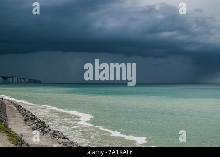 La plage d'Onival, l'arrivée d'un cumulonimbus arcus sur les falaises et sous le soleil. La mer est verte, turquoise avant le grain et le coup de vent. Banque D'Images