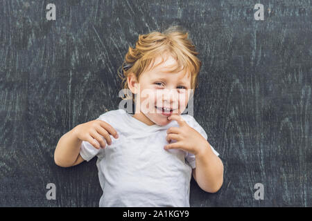 Vue de dessus d'une petite blonde enfant garçon avec de l'espace pour le texte et les symboles sur le vieux fond de bois. Concept de confusion, de réflexion et de choix Banque D'Images