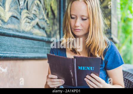 Belle femme de commander à partir d'un menu dans un restaurant et de décider quoi manger Banque D'Images