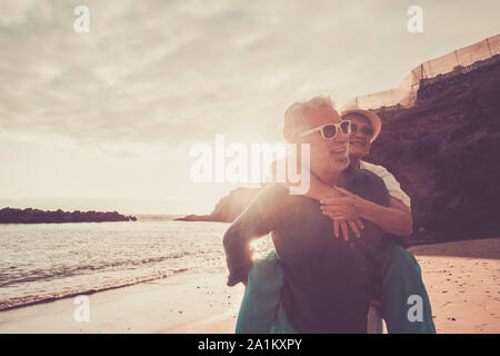 Beau couple de personnes âgées à la plage de s'amuser ensemble et à jouer - homme mûr porter sa femme femme avec l'amour et la vie pour toujours - concept mer ou Banque D'Images