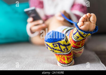 Close up of Paire de pieds à l'extérieur d'une drôle de couleur à la main cassée chaussettes - concept de vie différent et la vie à la maison - téléphone moderne dans backg Banque D'Images