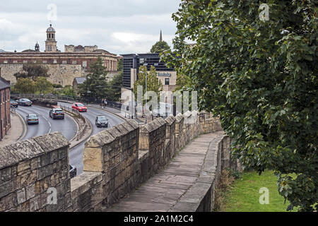 Aspect du mur romain de la ville de York, au Royaume-Uni avec arbres et herbe point contre ciel nuageux, et la circulation sur route adjacente en arrière-plan. Banque D'Images