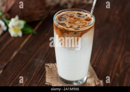 Café glacé à la noix de coco en grand verre. Boisson d'été à froid sur un fond de bois foncé Banque D'Images