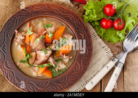 Ragoût d'agneau marocain avec carottes, oignons, persil, servis avec salade et tomates cerises sur table en bois rustique Banque D'Images